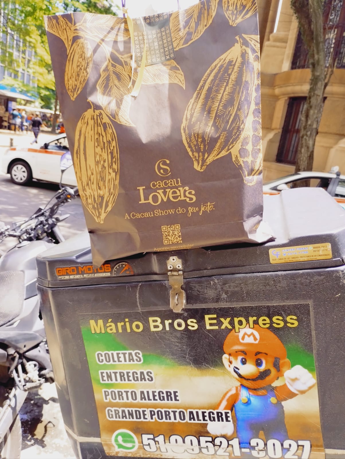 Baú de entrega da Mario Bros Express instalado em motocicleta com WhatsApp de contato